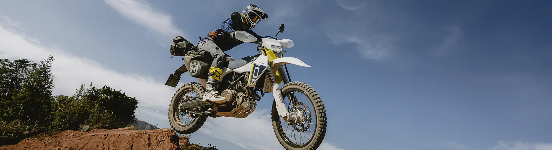 A Husqvarna Norden 901 Expedition rider is riding on a winding road with a forest in the background